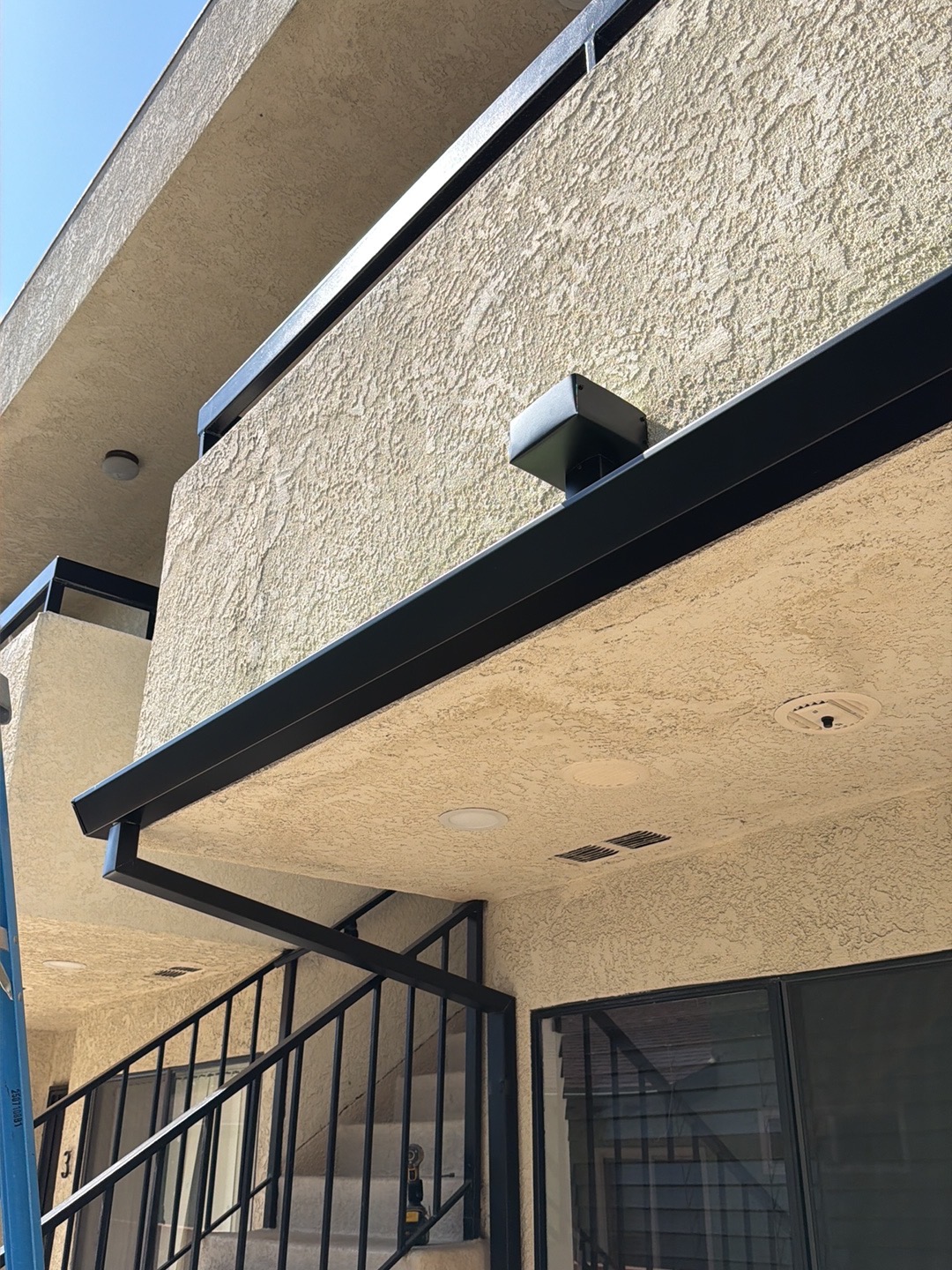 Close-up of black box gutter and downspout outlet on a stucco building in LA